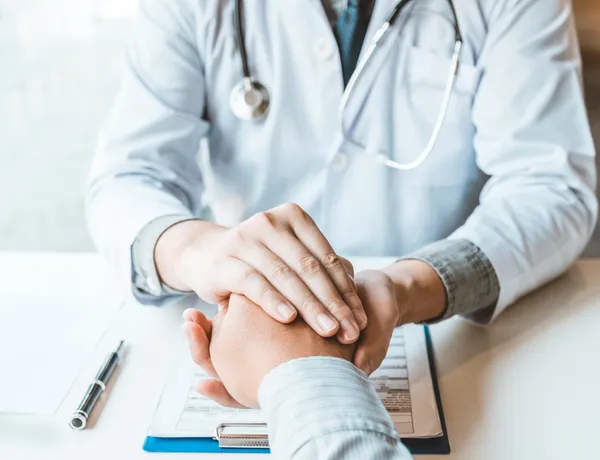 Provider holding patient's hands in a compassionate consultation